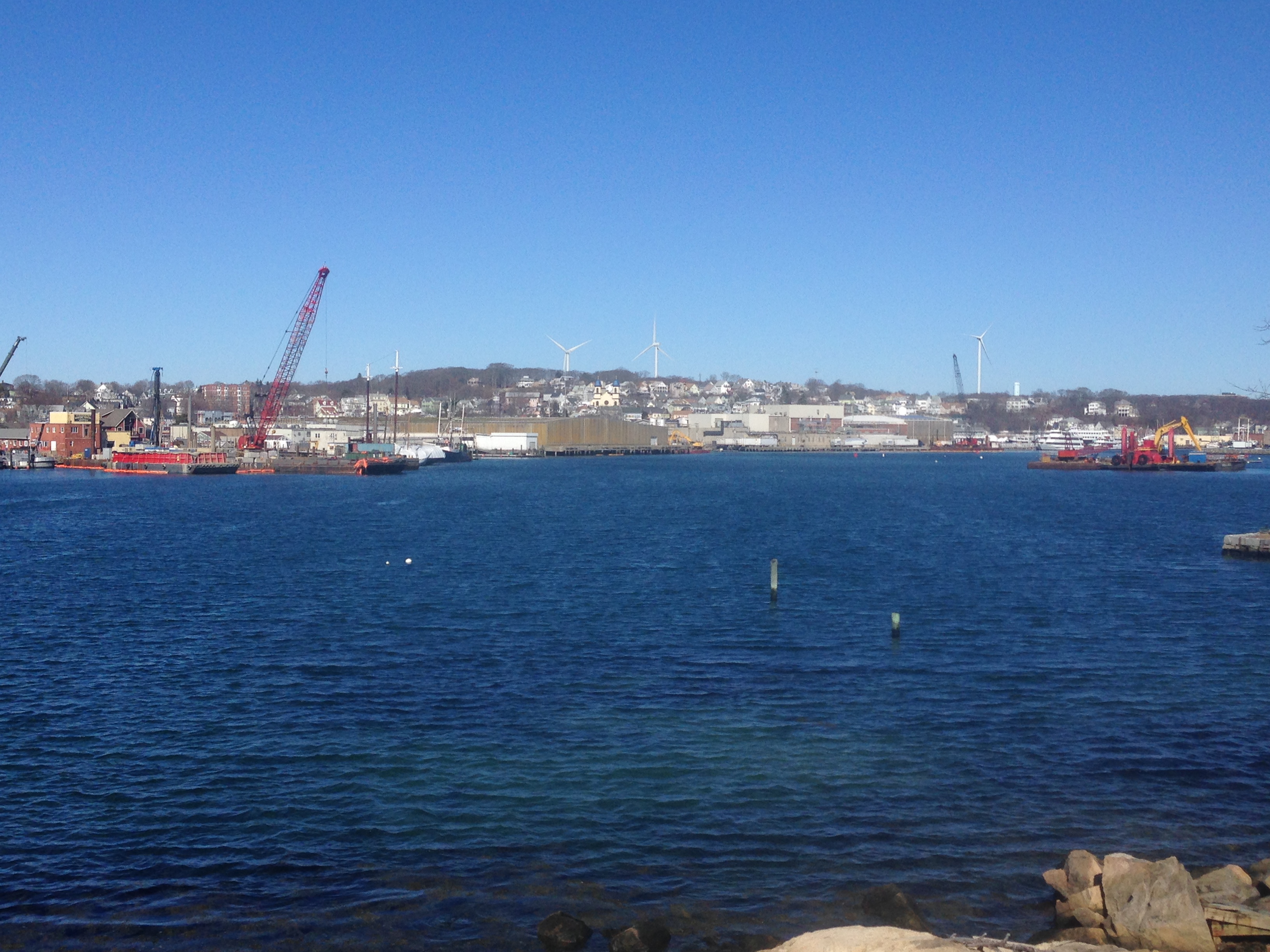 An image of a blue harbor with industrial equipment on the shore.